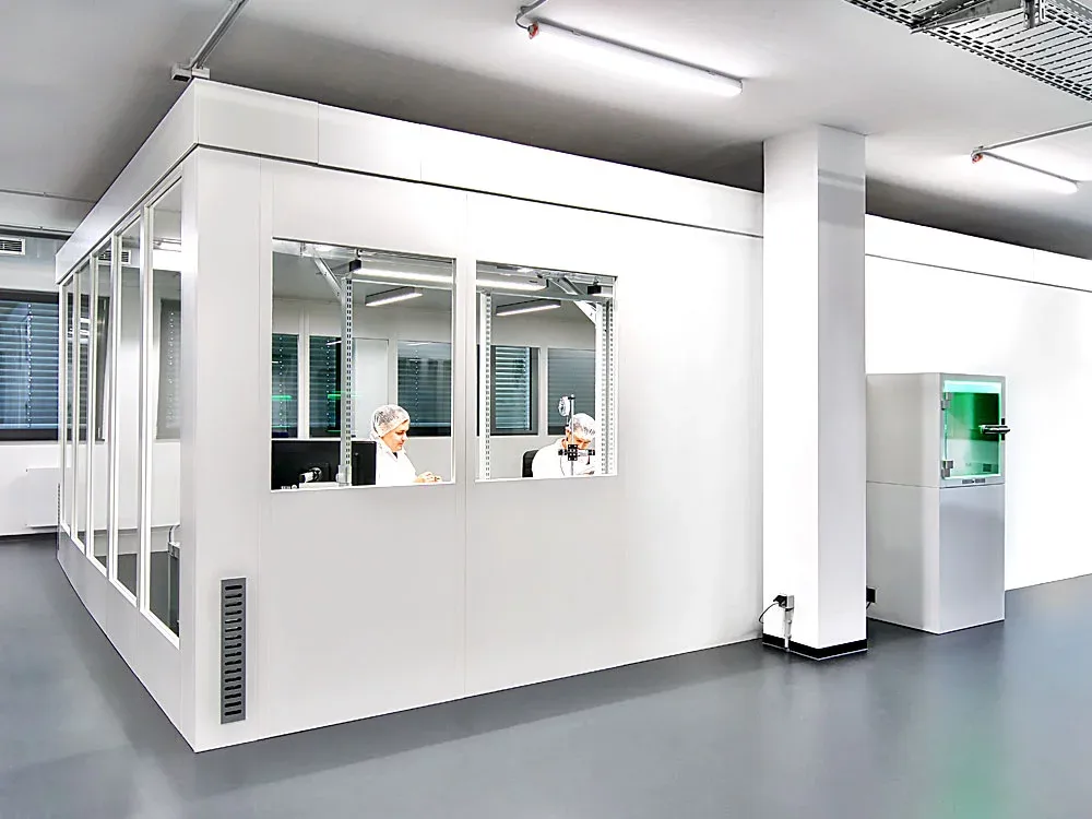 Modular ISO 6 cleanroom with white wall panels and windows, operators in gowns working inside